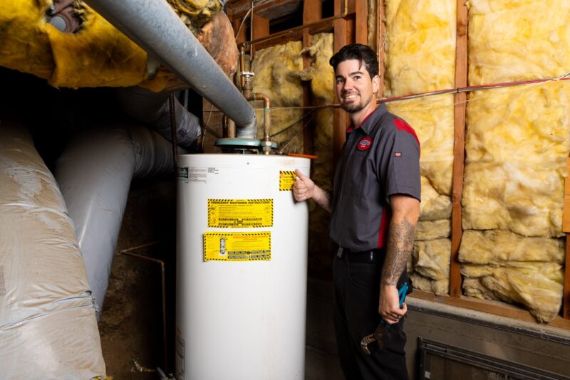 a Gotelli plumber holding a thumbs up while standing in front of a residential water heater