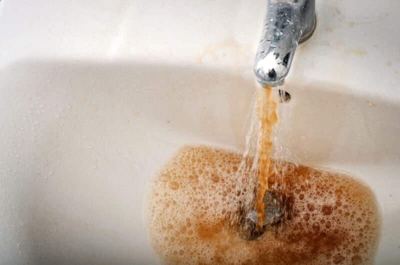 brown and rusty water coming from a bathroom sink faucet
