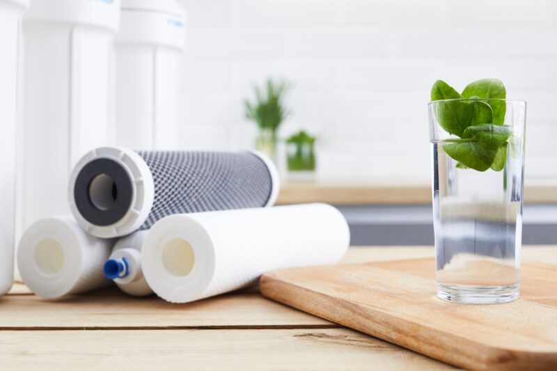 water filters stacked on a table next to a clear glass of water