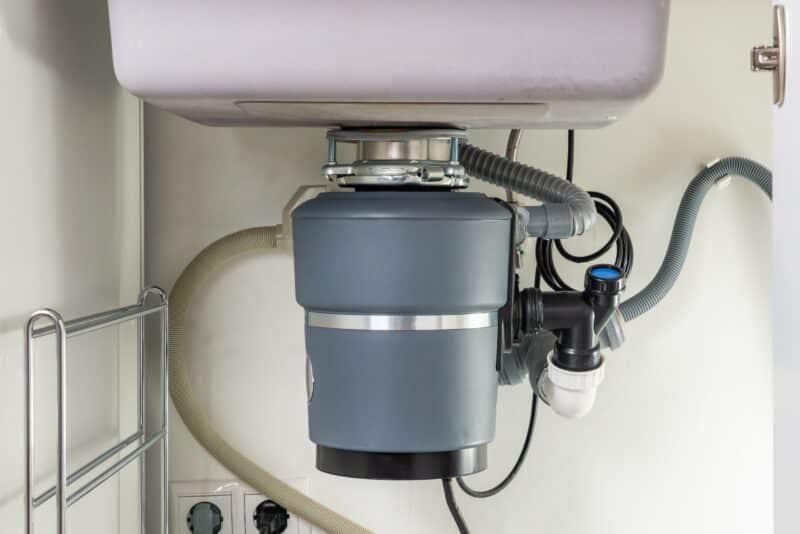 a garbage disposal system connected to the bottom of a kitchen sink