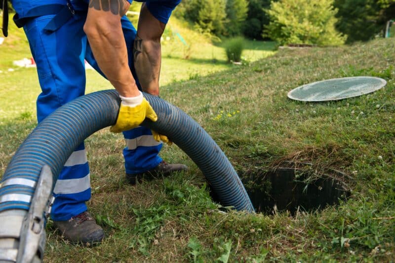 a plumber inserting a tube into a sewer to provide a sewer line clean-out