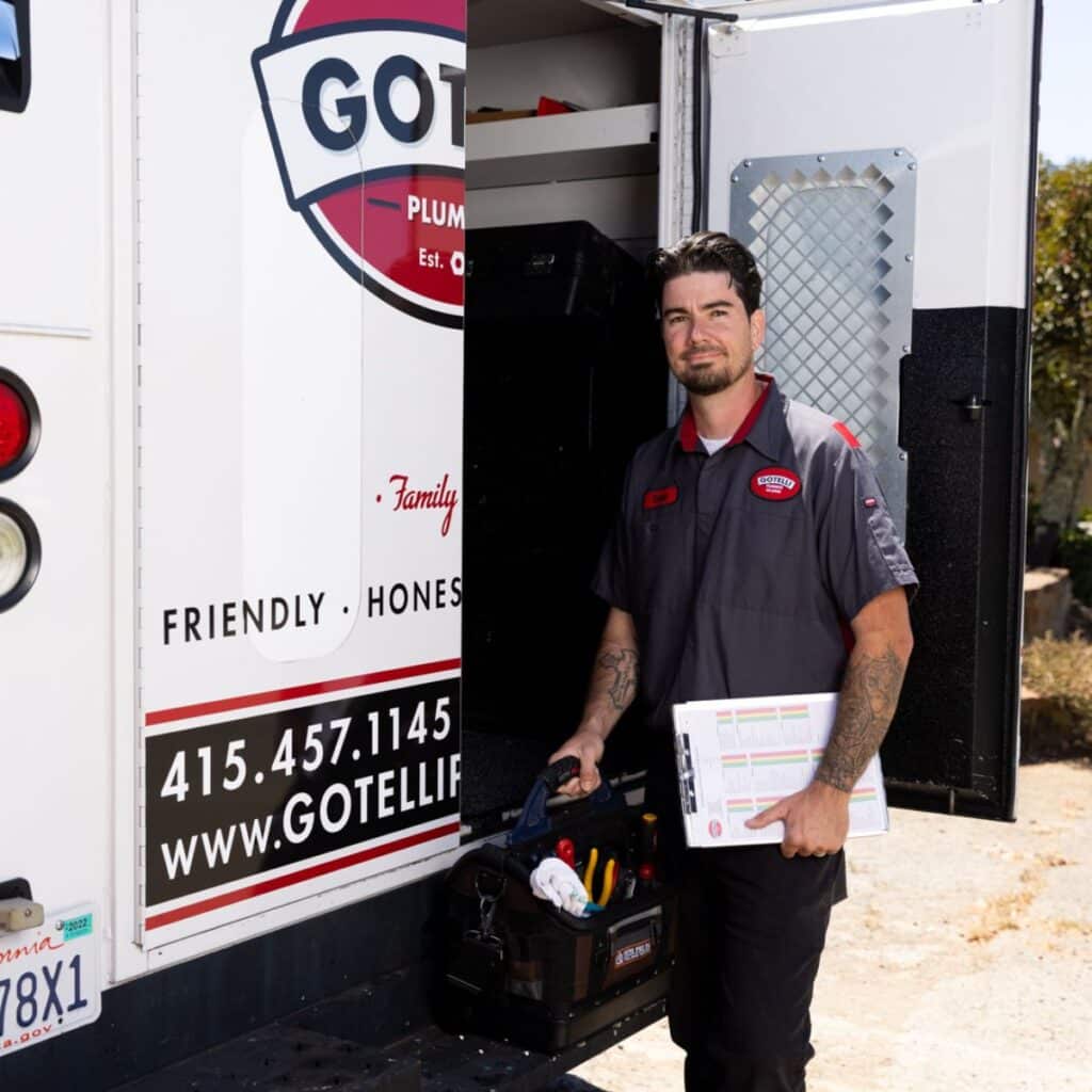 a Gotelli plumber standing outside of the company vehicle with tools in hand