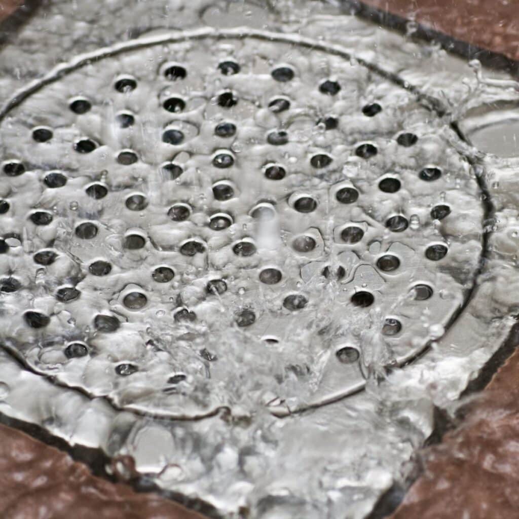 close up of a recently-cleaned shower floor drain with water flowing into it
