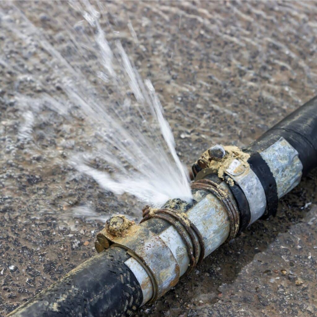 a damaged pipe system with a leak that has water spraying from it