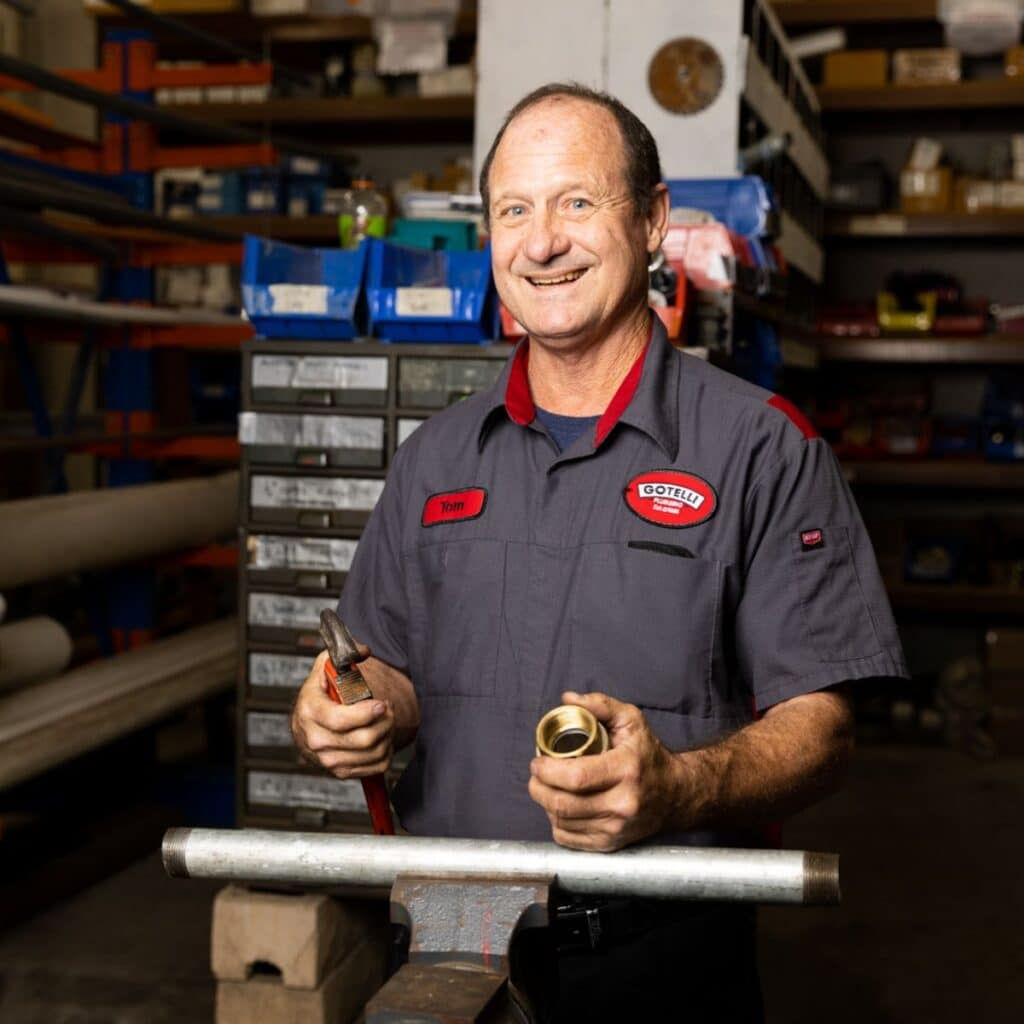 a Gotelli plumber smiling while holding plumbing equipment