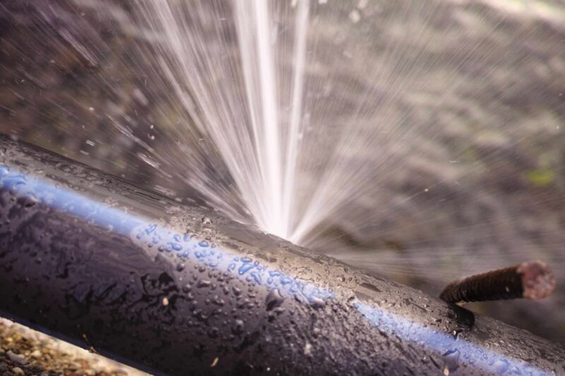 a damaged pipe with water spraying from a leak