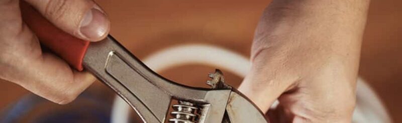 a pair of hands using a wrench to make pipe adjustments
