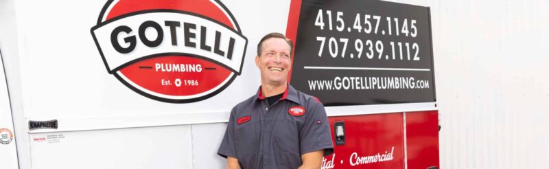 a Gotelli plumber standing in front of a company vehicle and smiling